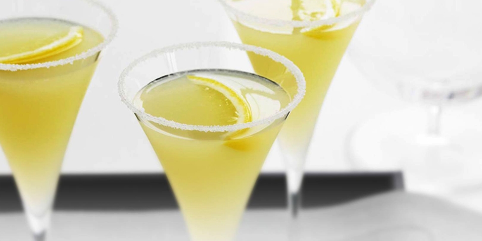 Three Grey Goose Vodka lemon drop cocktails garnished with lemon with a sugared rim.