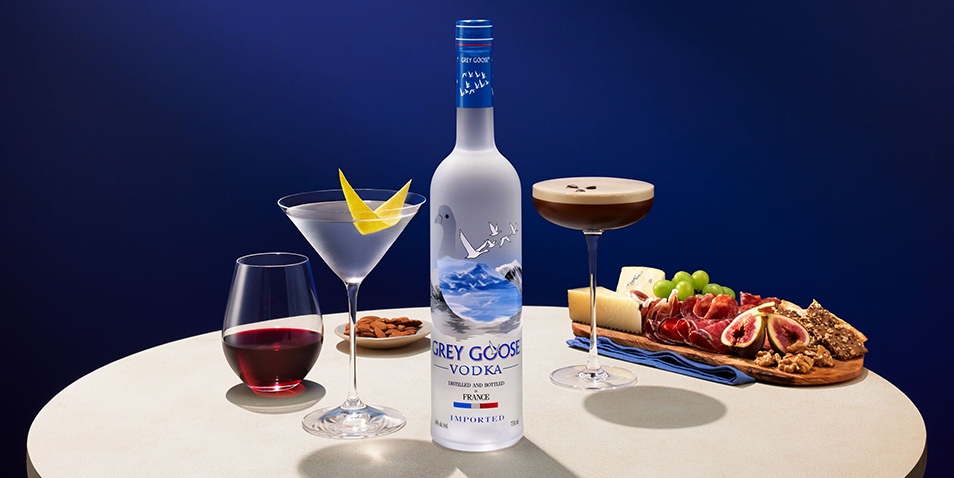 A bottle of Grey Goose vodka with an Espresso Martini Cocktail, Dry Martini Cocktail and charcuterie.